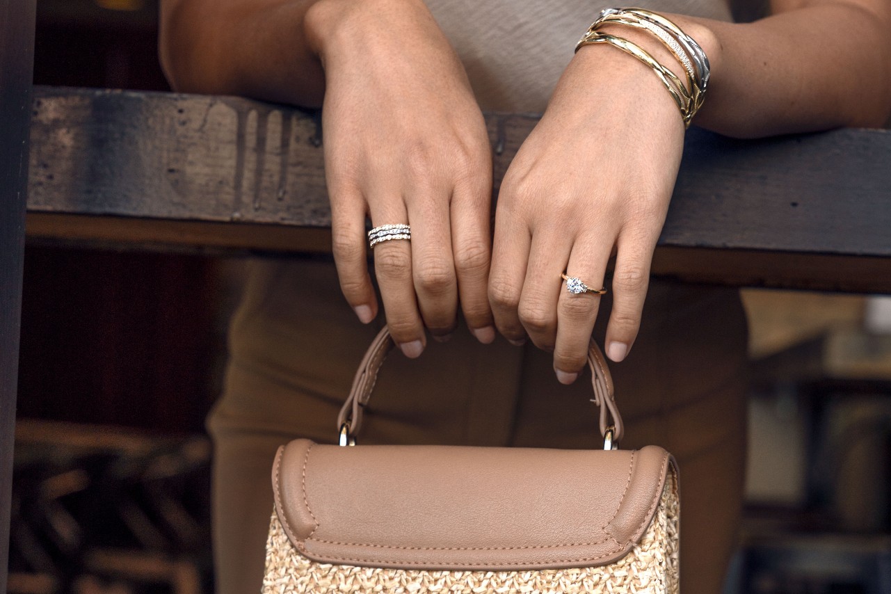 a lady’s hands wearing fashion jewelry by TACORI and holding a purse