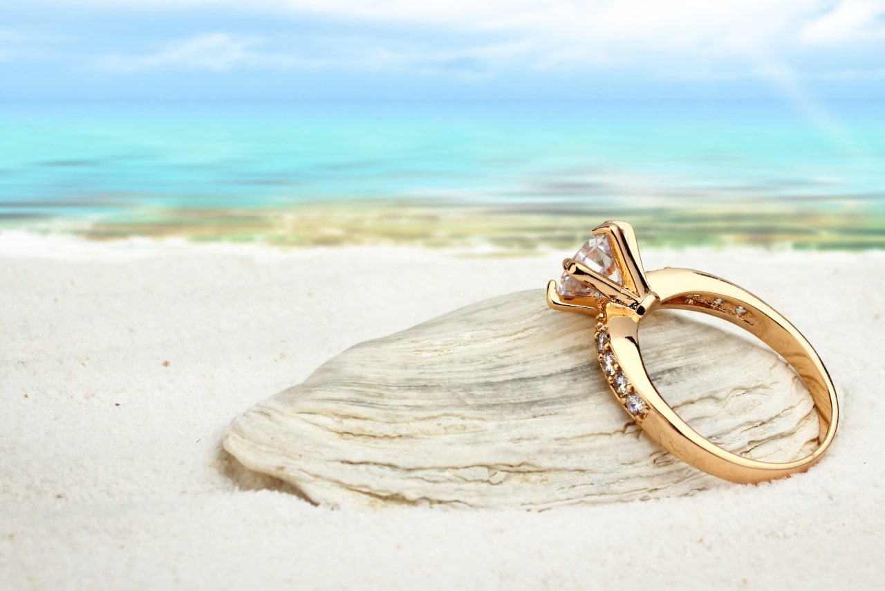 yellow gold engagement ring on a beach