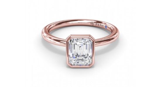 a rose gold engagement ring featuring a bezel set emerald cut center stone