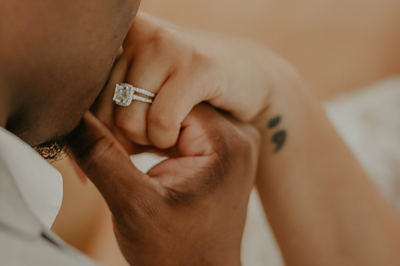 a man kissing his bride’s hand who is wearing a maximalist engagement ring