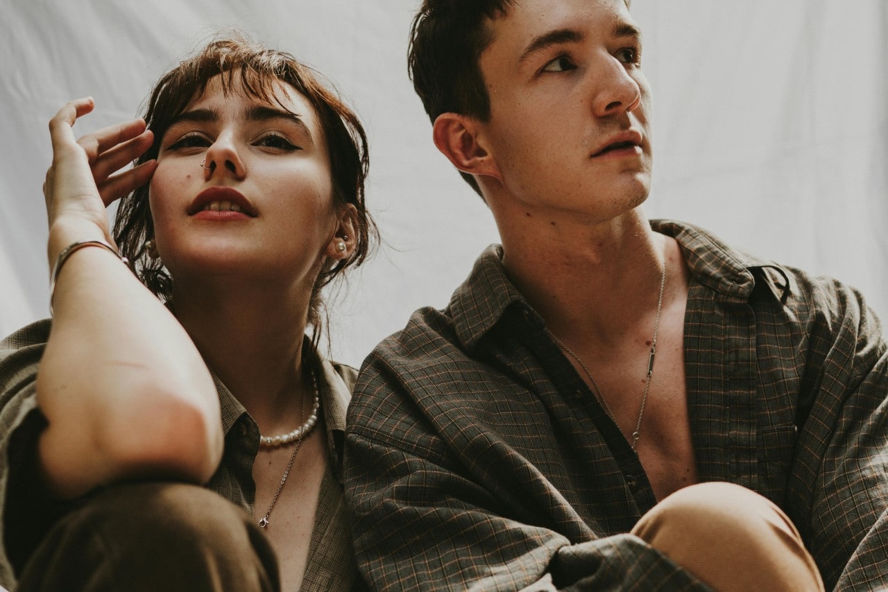 A view of a man and woman wearing fashion jewelry sitting next to each other.