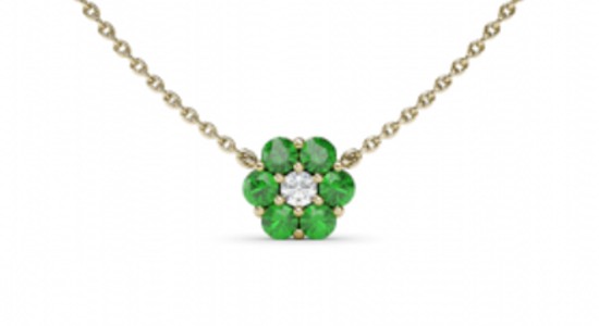 a yellow gold pendant necklace featuring emeralds and a diamond arranged into a flower shape