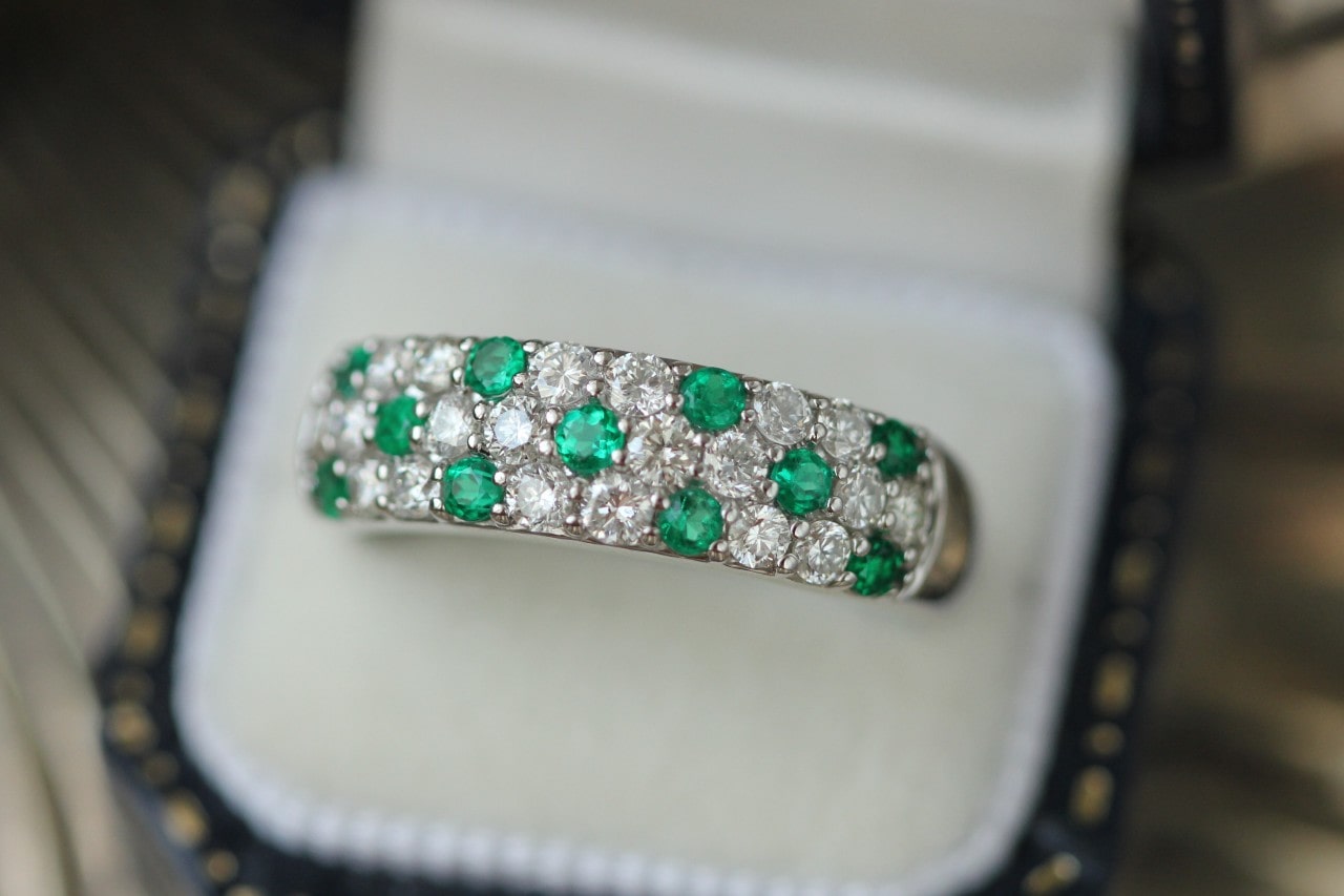 a diamond and green gemstone wedding band in a box