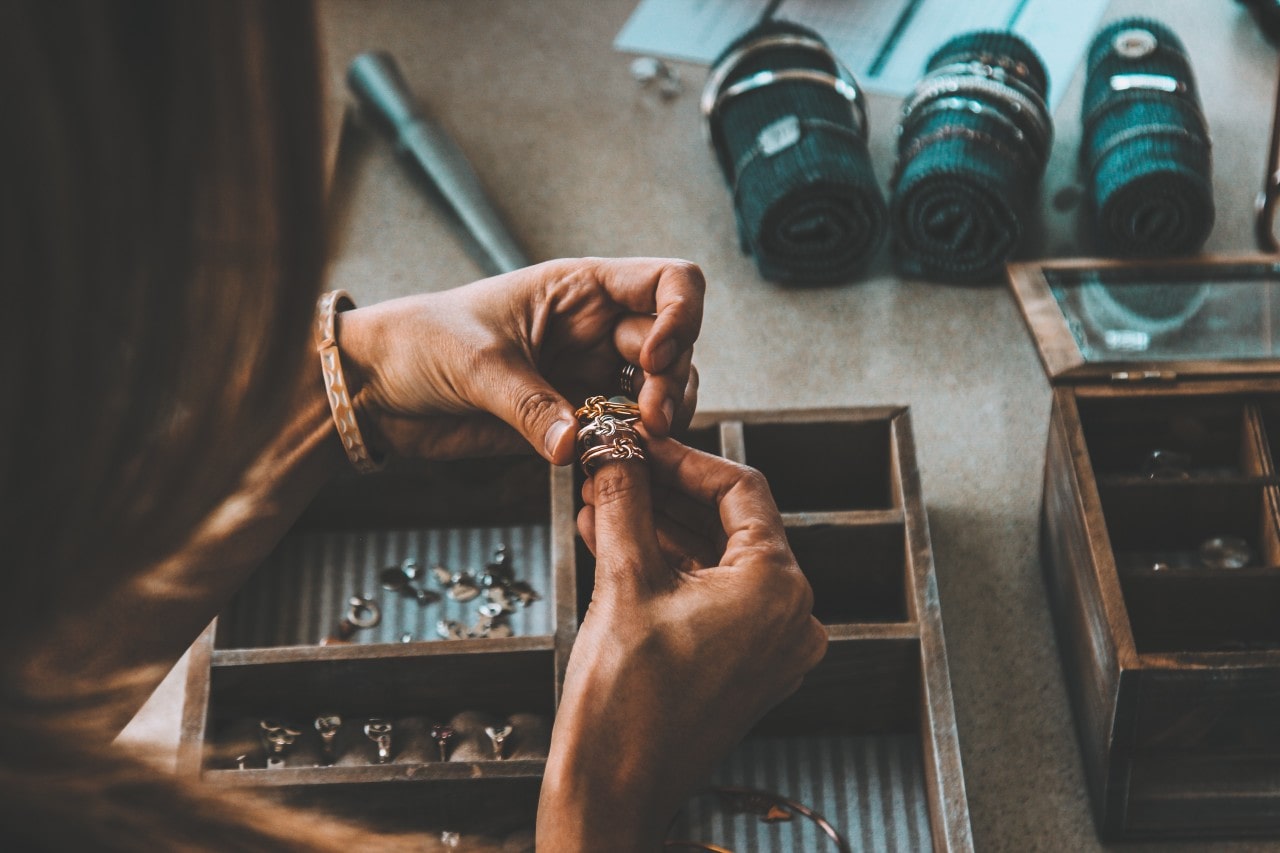 A woman compares three rings while she plans her ring stack.