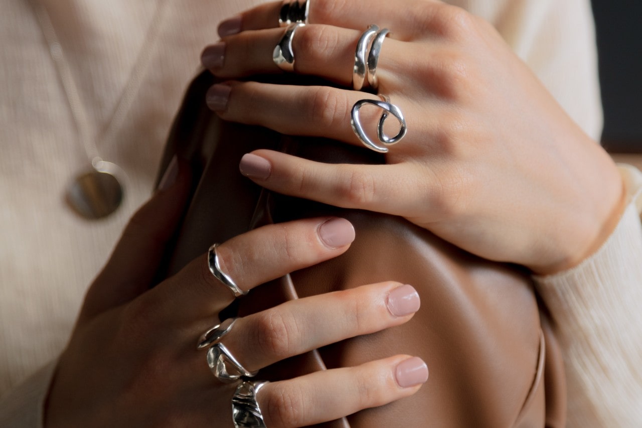 A woman wearing multiple sterling silver rings grabs a leather bag.