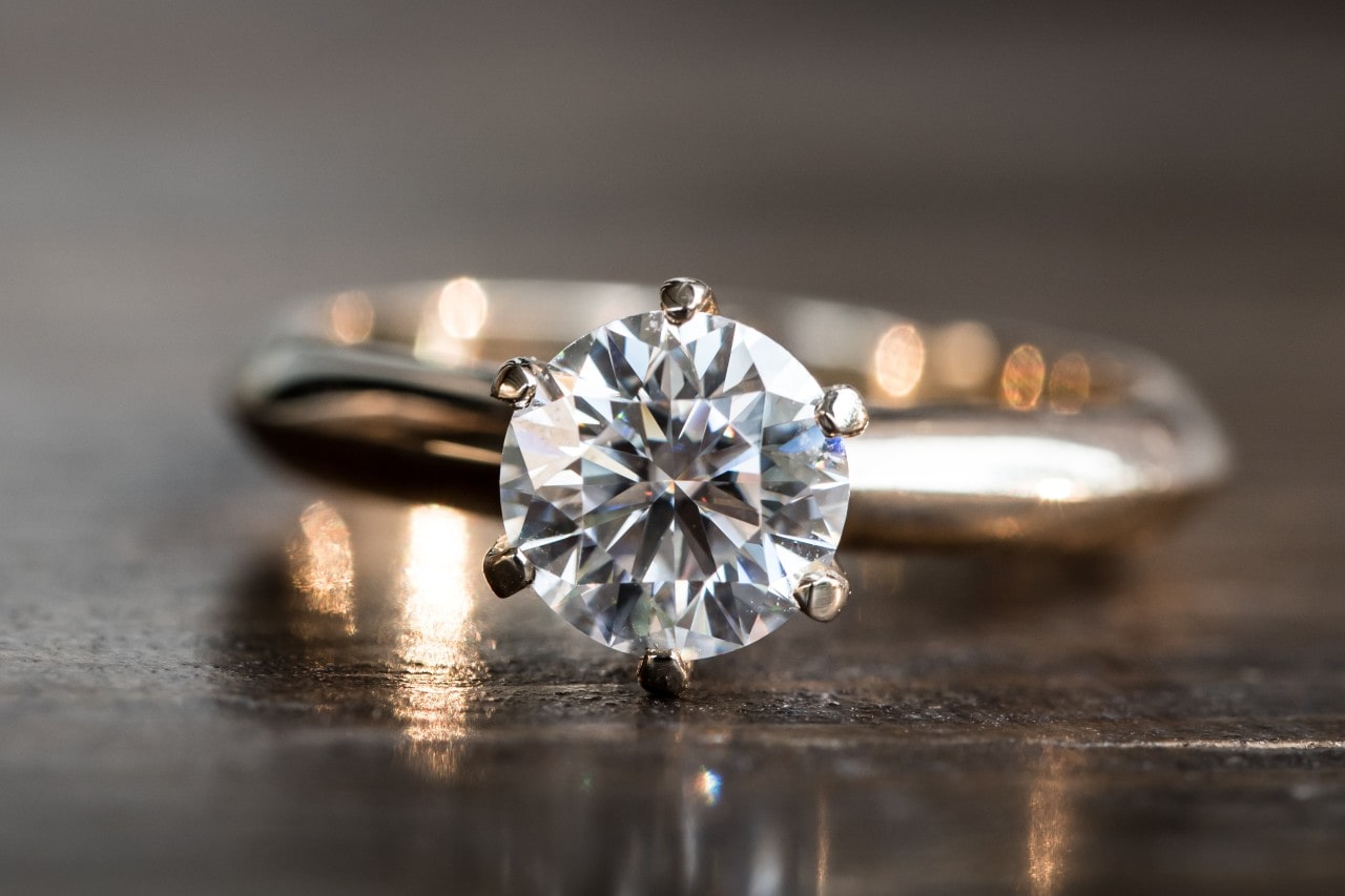 Platinum solitaire engagement ring sitting on a table.