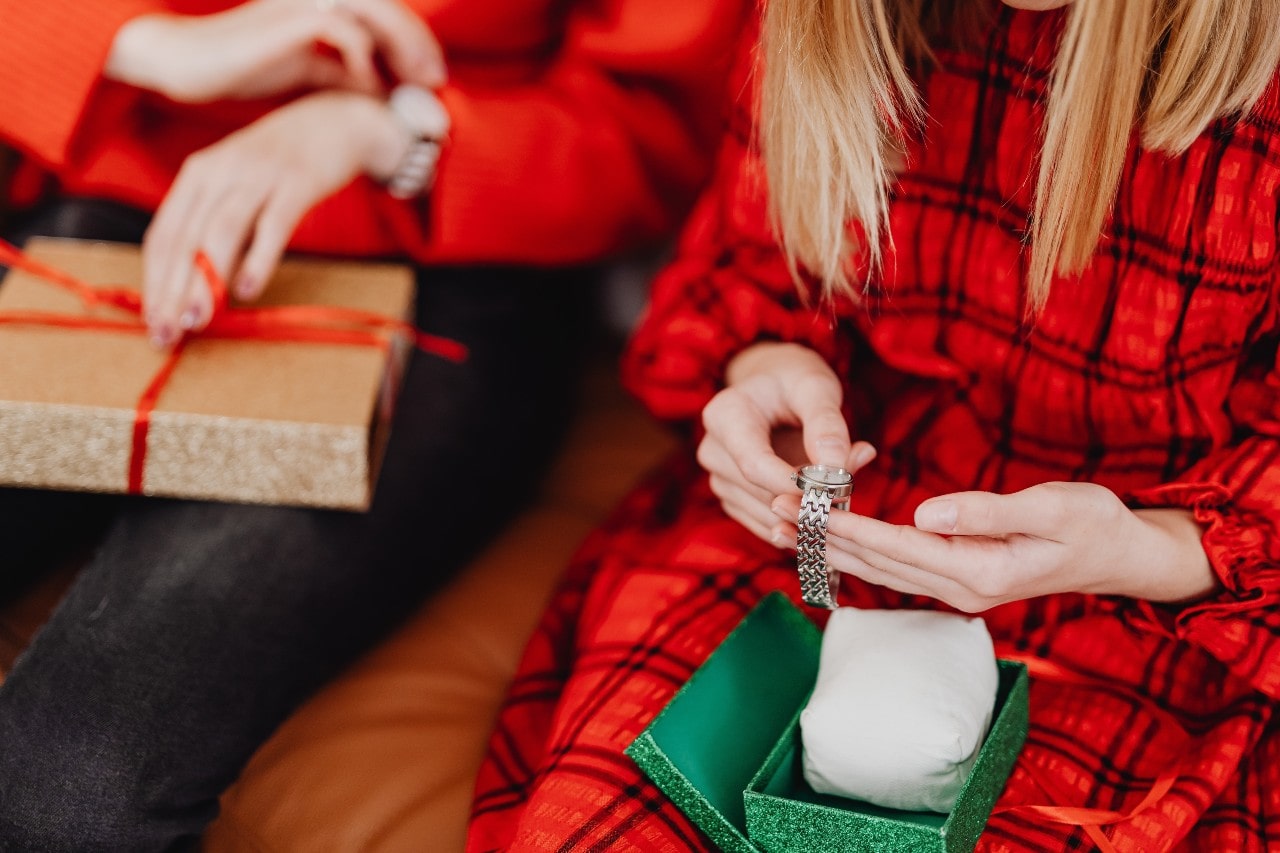 two people dressed festively opening boxes containing silver watches