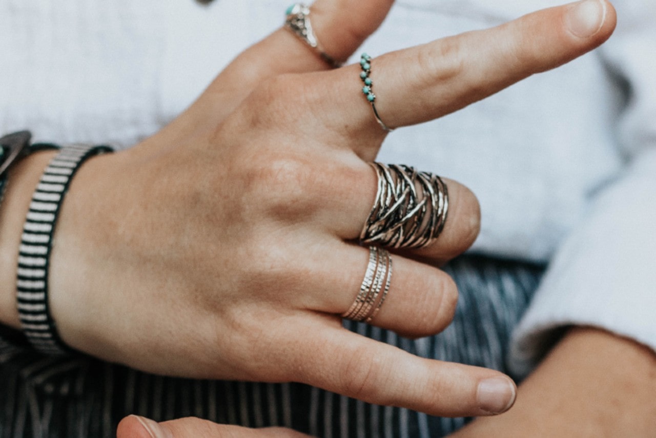 A person wearing multiple rings forms a sign with their hand.