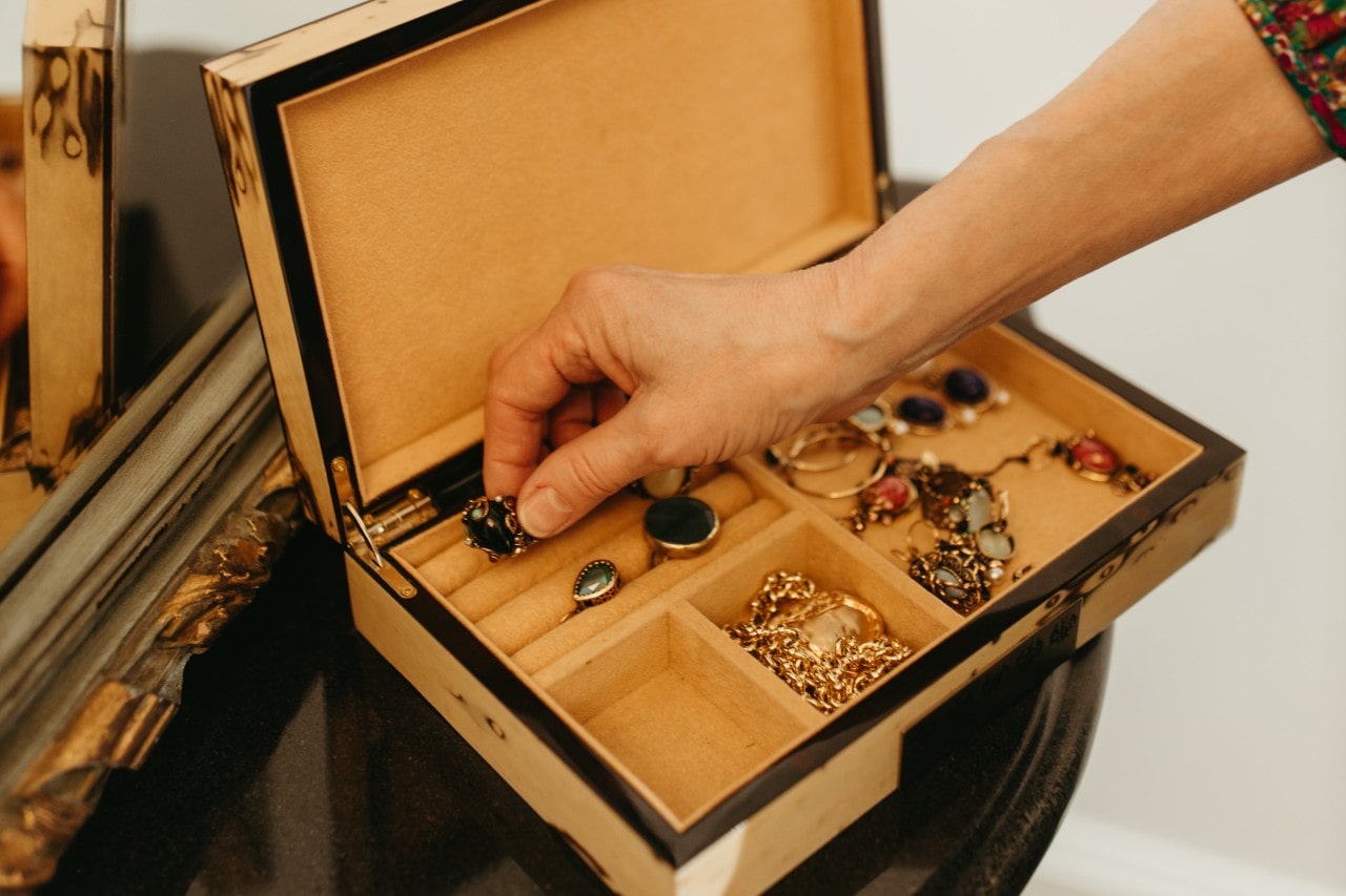 A woman takes a gemstone vintage ring out of her jewelry box.