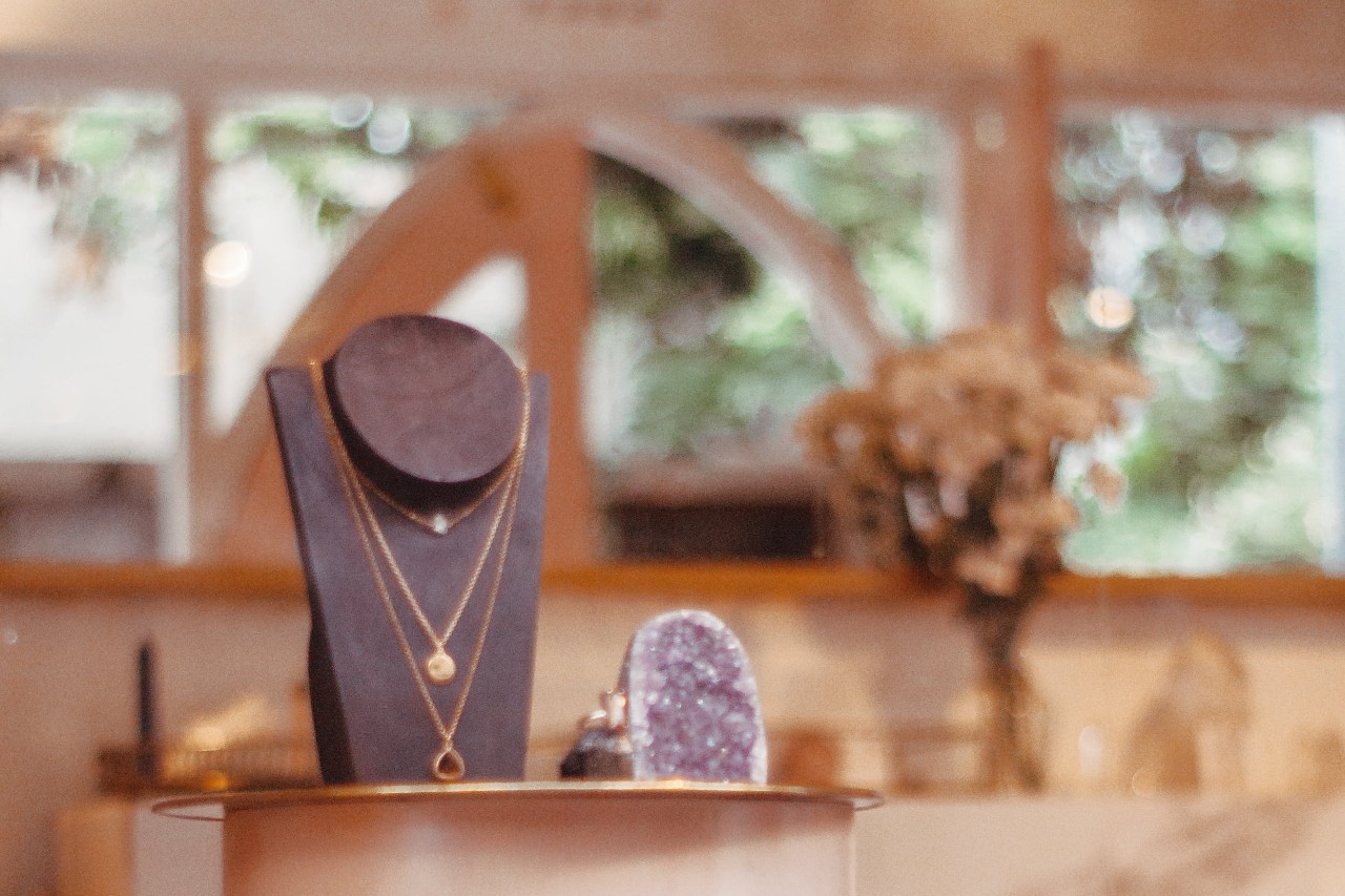 a jewelry store display with three layered necklaces on a stand next to a large purple gemstone