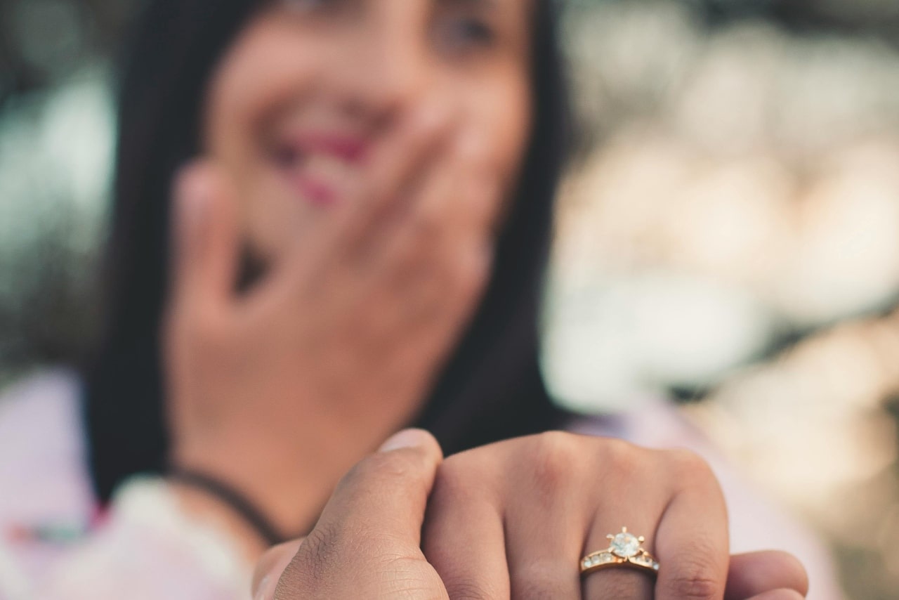 a man holding a woman’s hand who is wearing a yellow gold engagement ring