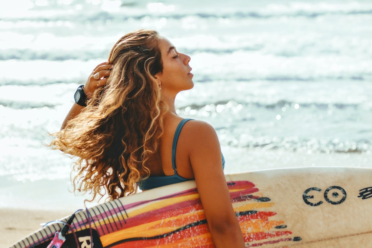 woman holding a surfboard and wearing a watch