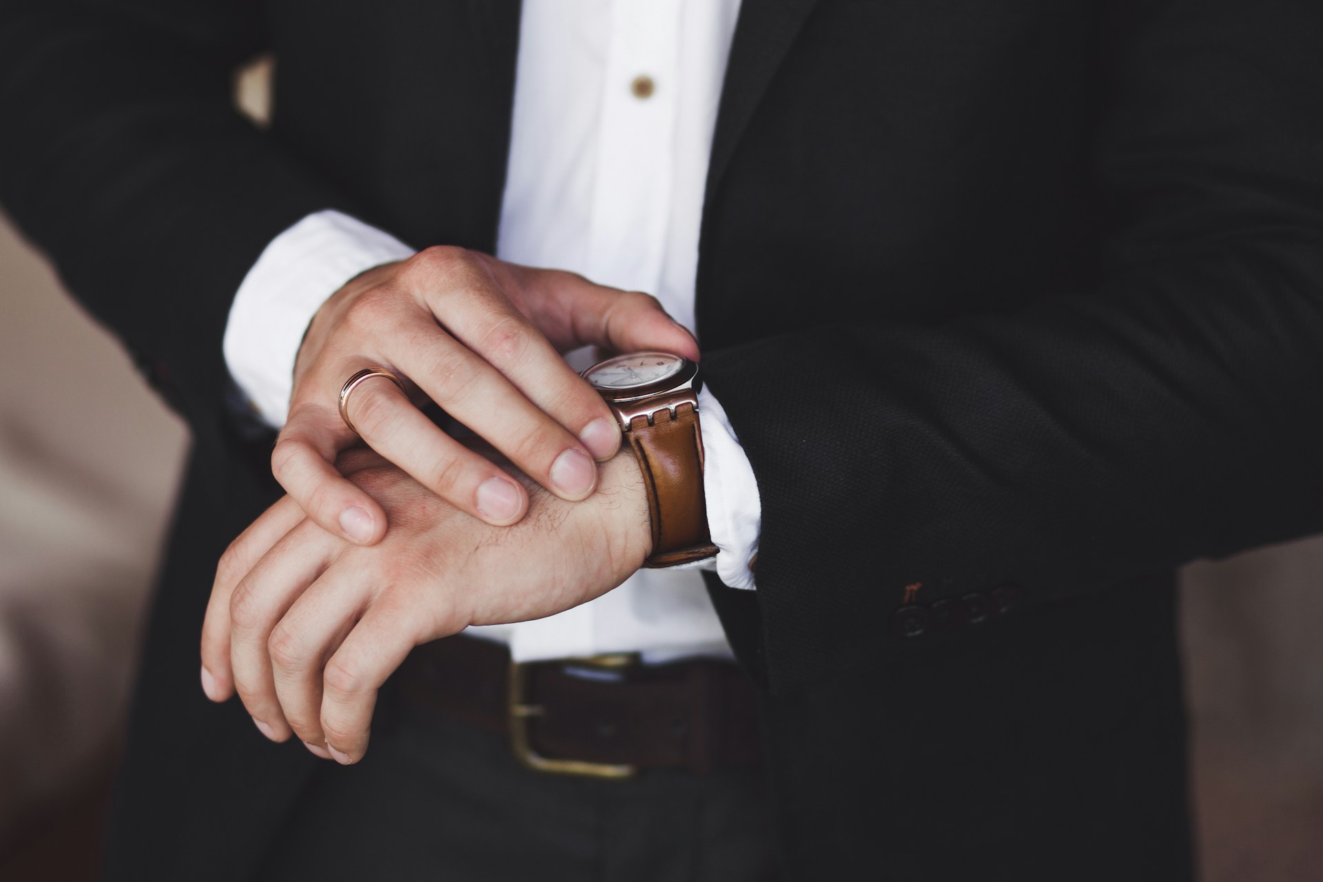 A close-up of a well-dressed man adjusting his luxury wristwatch.