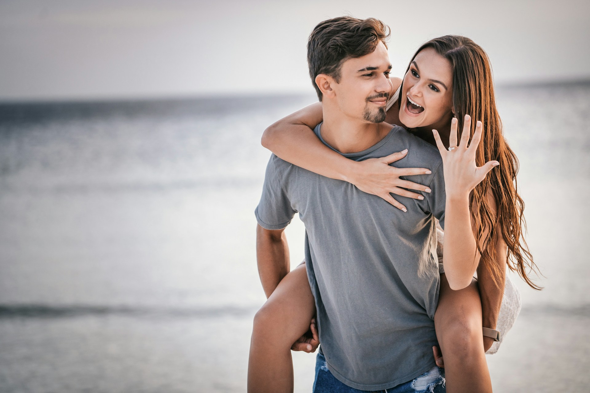 a lady riding on a man’s back wearing an engagement ring