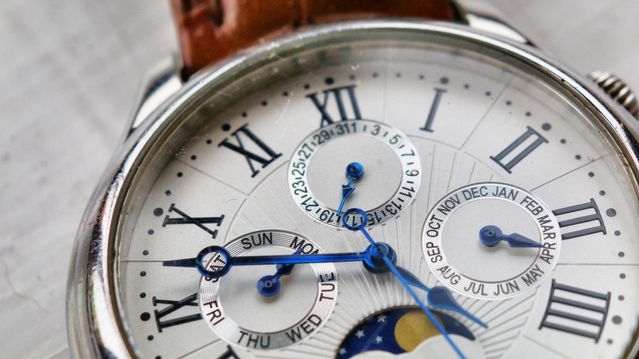 A close up of different time features on a silver watch.