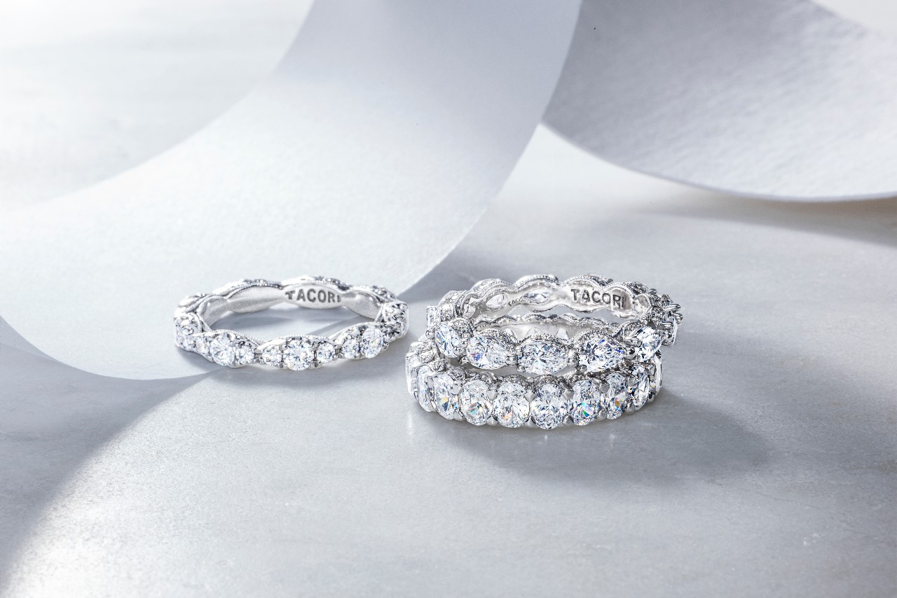 three white gold diamond wedding bands by TACORI on a white surface