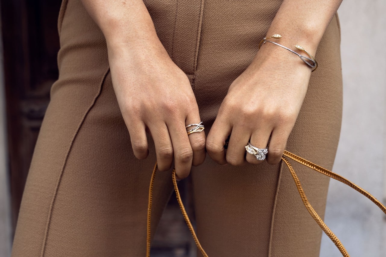 close up image of a woman’s hands holding the straps of a purse and wearing Tacori jewelry
