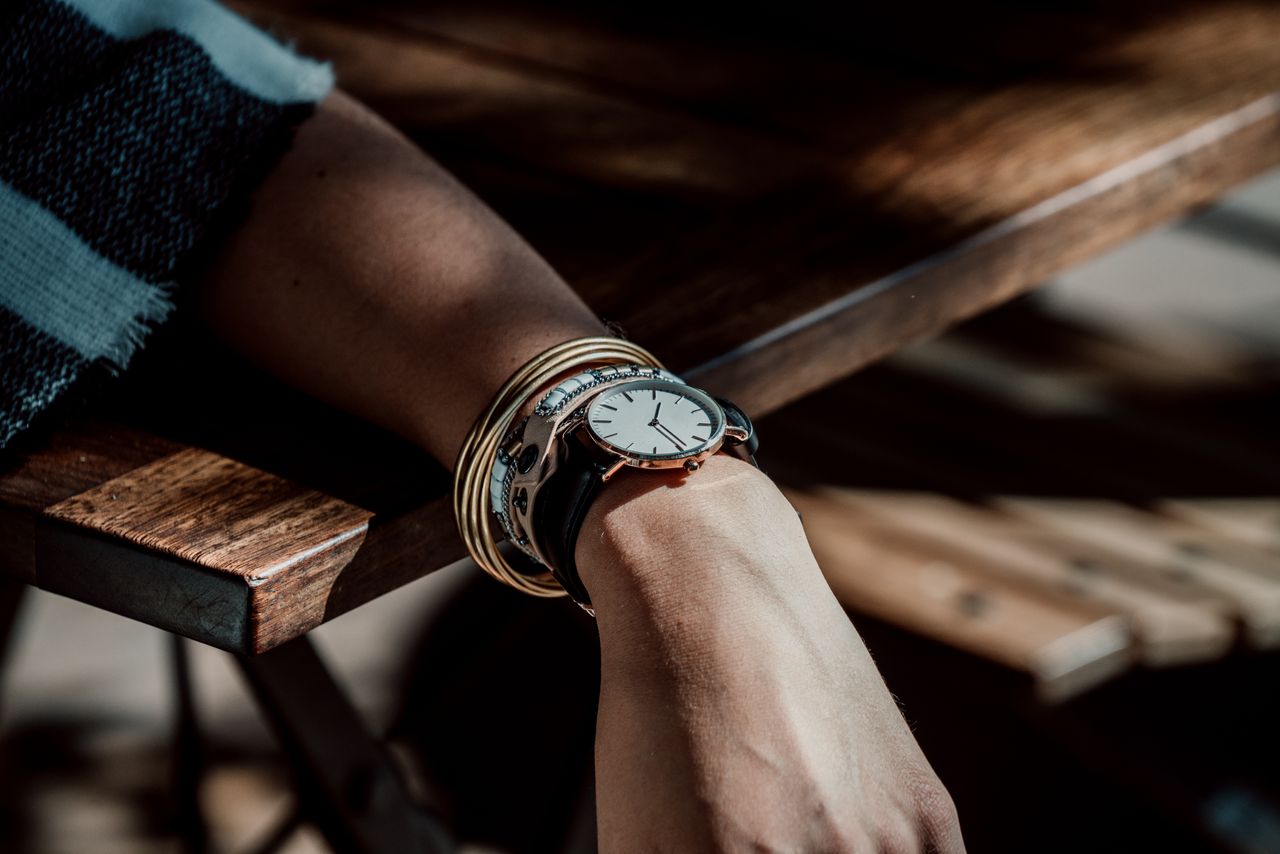 A closeup of a woman’s wrist wearing a watch and multiple bangles.