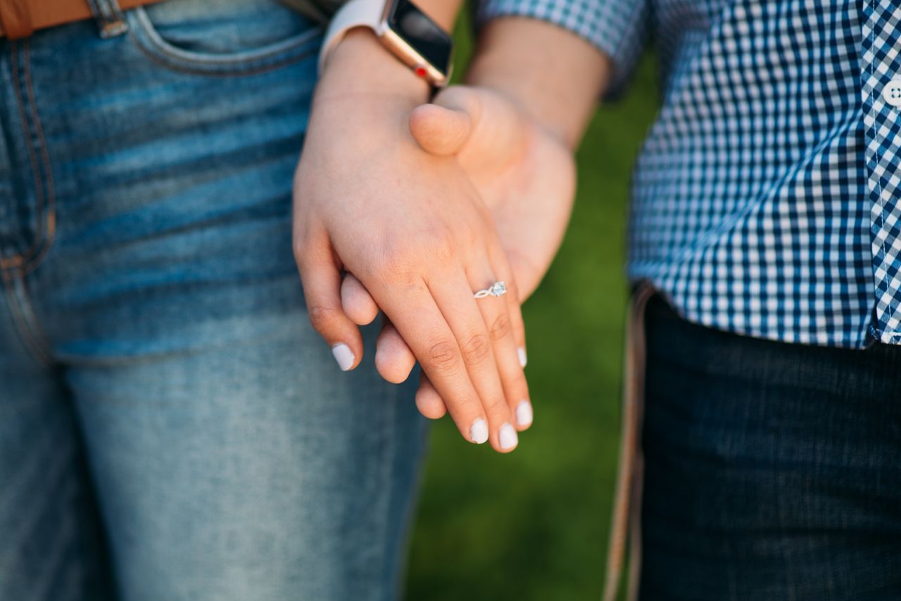 A couple holds hands, showing off her Christopher Designs engagement rings.