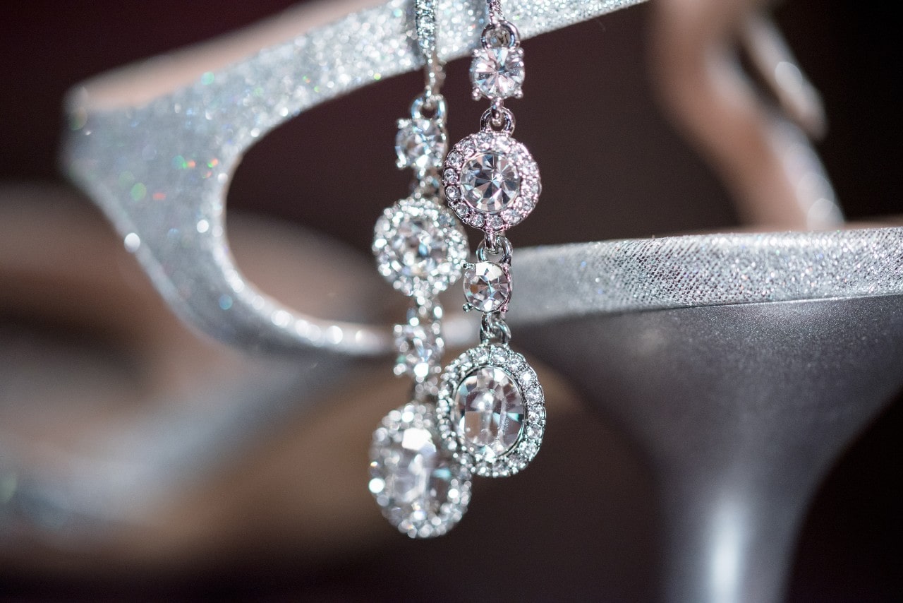 A pair of diamond drop earrings dangling from a silver glittery heel. A pair of diamond drop earrings dangling from a silver glittery heel.