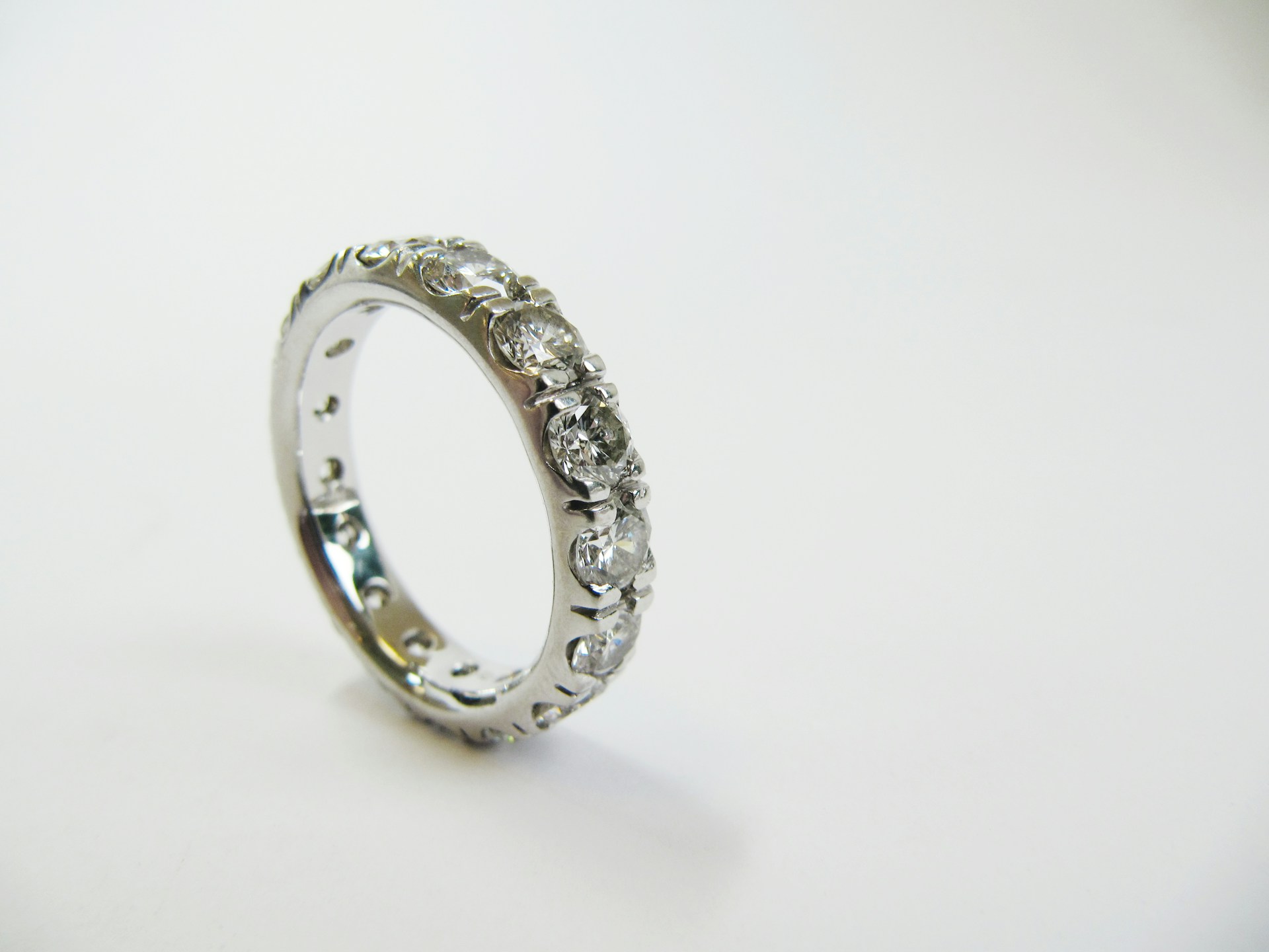 a white gold eternity diamond wedding band against a white surface