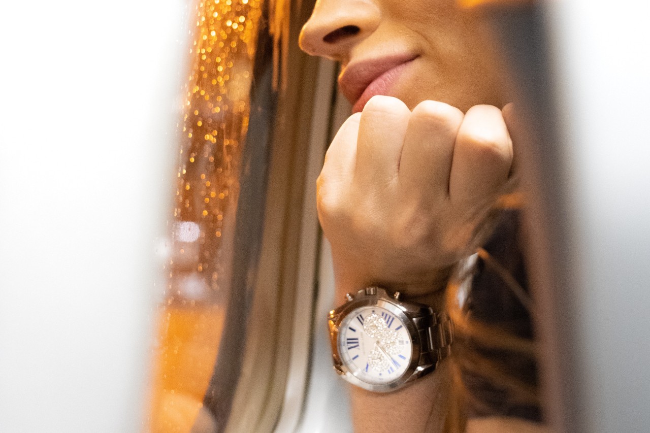 A close up of a woman leaning towards airplane window, showcasing her luxurious metallic wristwatch with diamond accented dial A close up of a woman leaning towards airplane window, showcasing her luxurious metallic wristwatch with diamond accented dial