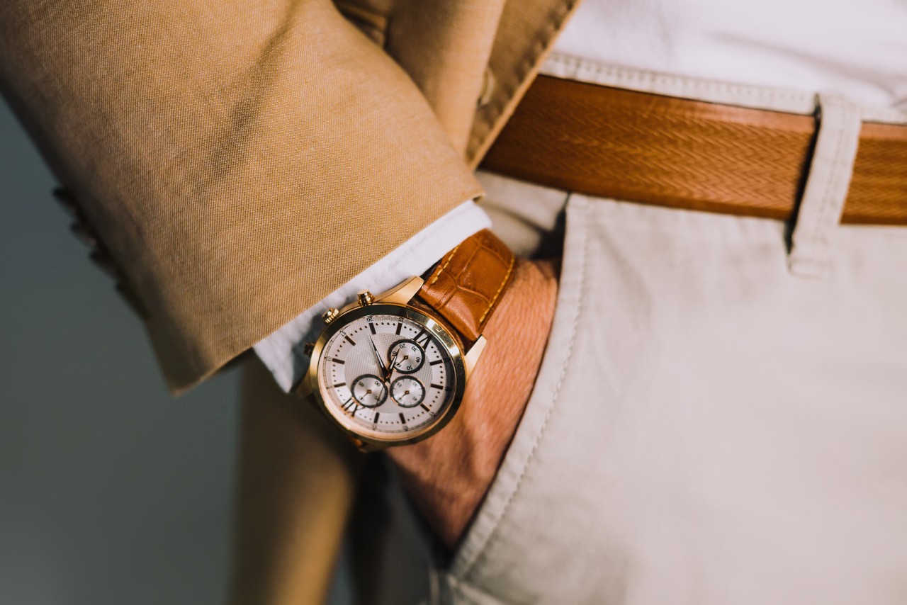 A close up of a person’s hand in a pocket, demonstrating brown leather wristwatch with white dial and several complications. A close up of a person’s hand in a pocket, demonstrating brown leather wristwatch with white dial and several complications.