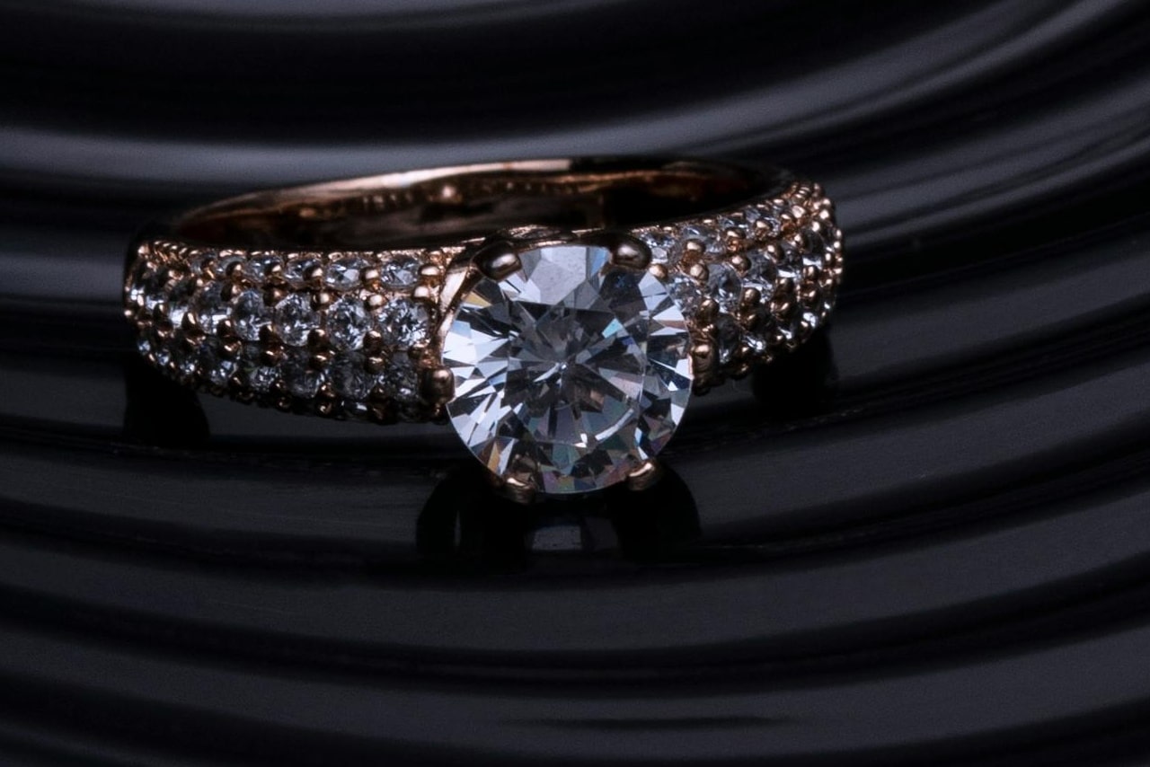 A close up of a rose gold double row engagement ring with a center round diamond.
